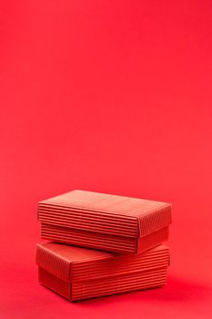 Monochromatic photo of two red closed corrugated cardboard boxes on red background. Valentine's Day gift packaging concept