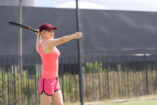 Woman playing tennis holding a racket and smiling