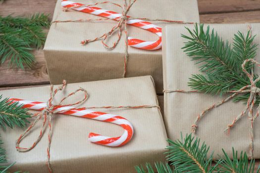 Christmas presents or gift box wrapped in kraft paper with decorations and fir branch on rustic wooden background