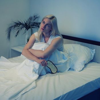 Sleep Disorders, insomnia. Woman Suffering From Depression Sitting On Bed In Pajamas - Image toned