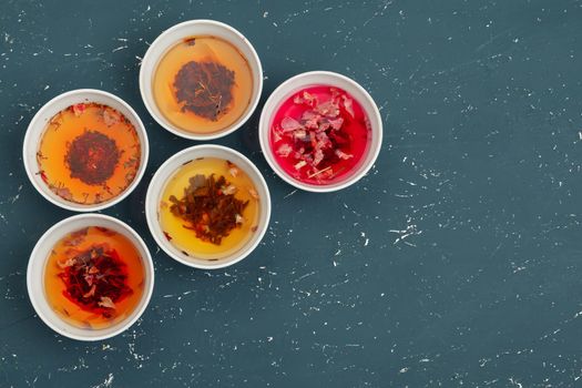 Tea concept. Different kinds of dry tea in ceramic bowls and cups of aromatic tea