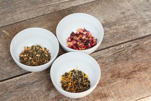 Aromatic dry tea in bowls on wooden background