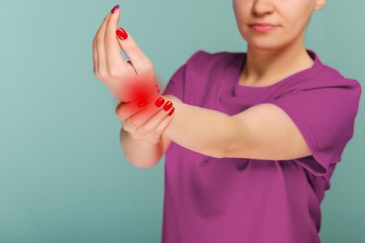A woman massaging her painful hand isolated on a blue background