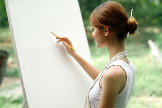 an artist in nature draws on an easel with a pencil. High quality photo