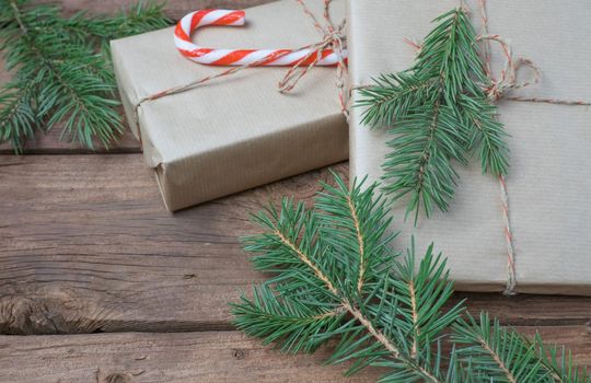 Christmas presents or gift box wrapped in kraft paper with decorations and fir branch on rustic wooden background