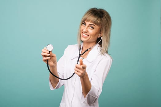 Young female doctor with stethoscope on foreground. Cut out of face isolated on blue background