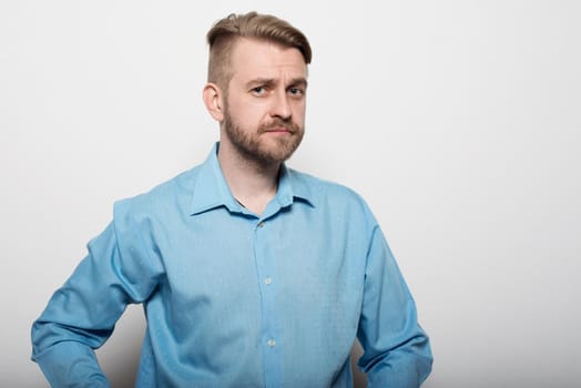 Hipster man in blue long-sleeved shirt, studio shot.