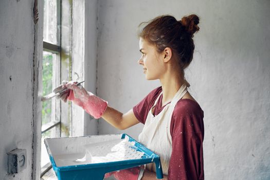 woman painter makes home repairs near window interior. High quality photo