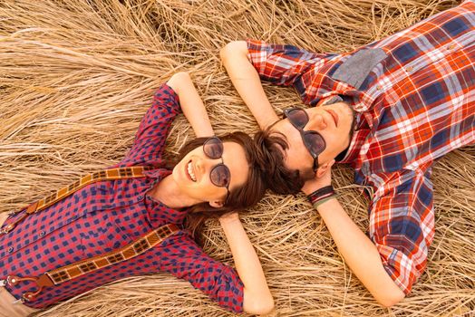 Young hipster couple in love rests on dry grass