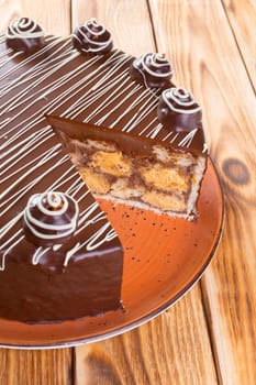 Cut chocolate cake on plate on wooden table close up