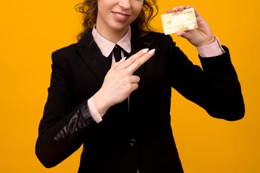 Portrait of a beautiful young business woman standing isolated over yellow background, holding credit card - image