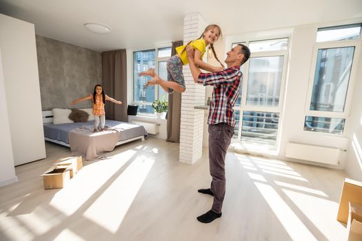 happy father and two children playing and cuddling at home on floor