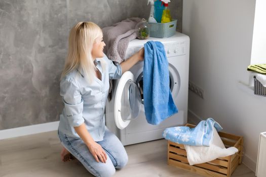 A young housewife with washing machine and clothes. Washing day.