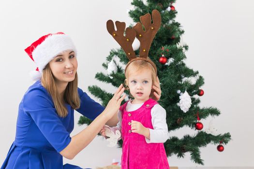 Christmas concept - mother and her little daughter with Christmas tree at living room.