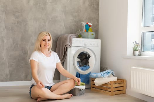 A young housewife with washing machine and clothes. Washing day.
