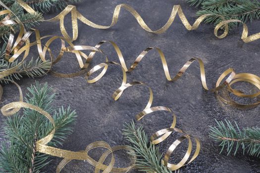 Christmas composition of fir branches and a gold ribbon on a black oil with gold embossing background