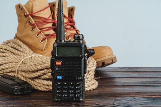 Equipment set for traveler including hiking boots and walki-talkie on wooden board