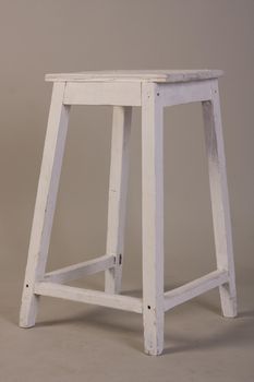 Old wooden white stool on a gray background.
