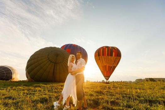 Beautiful romantic couple hugging at meadow. hot air balloon on a background