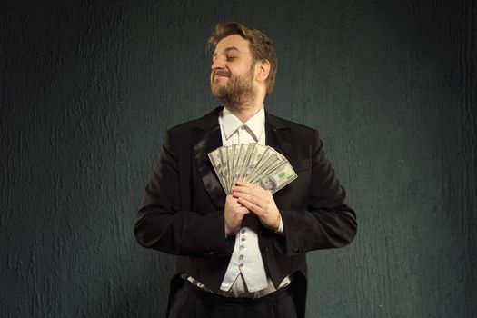 Positive man in a tailcoat hold money. - image