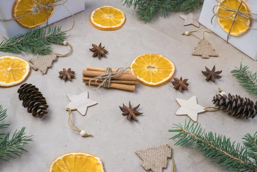 New Year's composition. On beige craft paper, gift boxes, dry orange slices, pine cones, cinnamon, cloves, spruce branches. Cozy Christmas concept