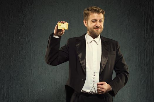 Positive man in a tailcoat offers a credit card. - image