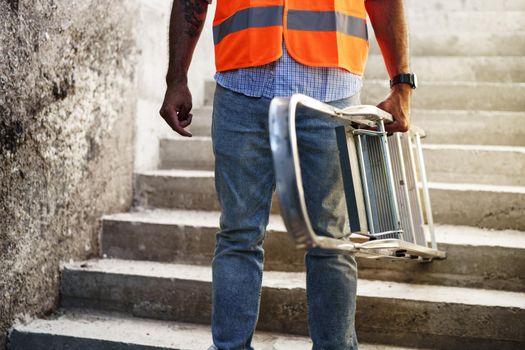 Professional builder carrying metal ladder, close up photo