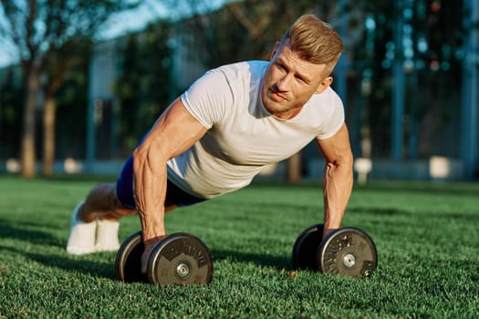 athletic man training with dumbbells in the morning Park. High quality photo