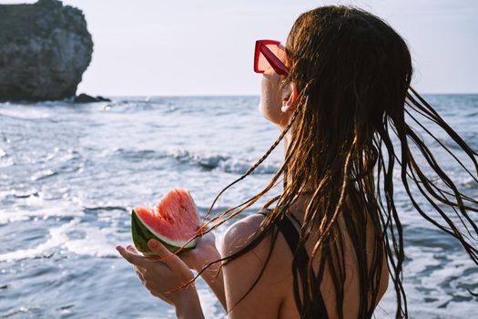 pretty woman in a black swimsuit with a watermelon in her hands summer Ocean. High quality photo