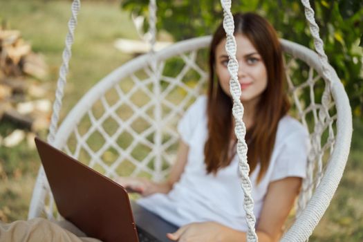 cheerful woman outdoors in hammock with laptop rest. High quality photo
