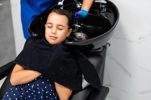 Pretty young girl's hair being arranged at the hair stylist