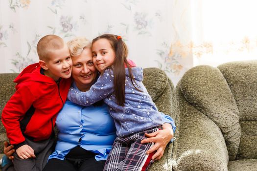 Grown up adult smiling grandchildren embraces elderly grandmother glad to see missing her, visit of loving relatives enjoy communication, cuddle as symbol of connection, love and support concept