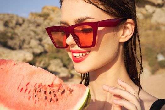 cheerful woman in sunglasses and watermelon nature rocks. High quality photo