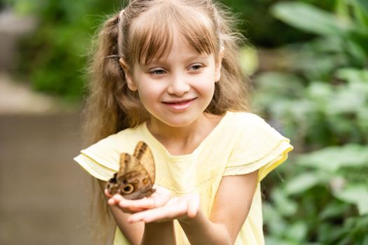 Little girl holding butterfly in her hand.