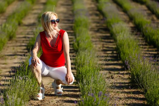 Beautiful provence woman relaxing in lavender field watching on sunset holding basket with lavanda flowers. blond lady in blossom field