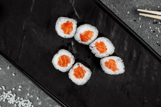 Simple maki with fresh salmon. Sushi on a gray background.