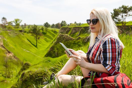 woman hiker use tablet pc sit on seaside mountain peak rock