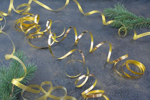 Christmas composition of fir branches and a gold ribbon on a black oil with gold embossing background