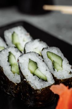 Delicious, juicy and mouth-watering maki with cucumber. Sushi on a gray background.