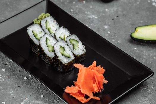 Delicious, juicy and mouth-watering maki with cucumber. Sushi on a gray background.