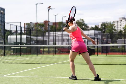 Pretty sportswoman with racquet at the tennis court. Healthy lifestyle