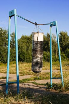 old punching bag hangs on a bar on an abandoned sports ground. The Concept of a Healthy Lifestyle