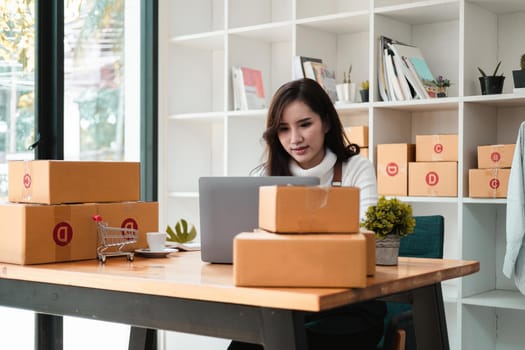 Starting Small business entrepreneur SME freelance,Portrait young woman working at home office, BOX,smartphone,laptop, online, marketing, packaging, delivery, SME, e-commerce concept