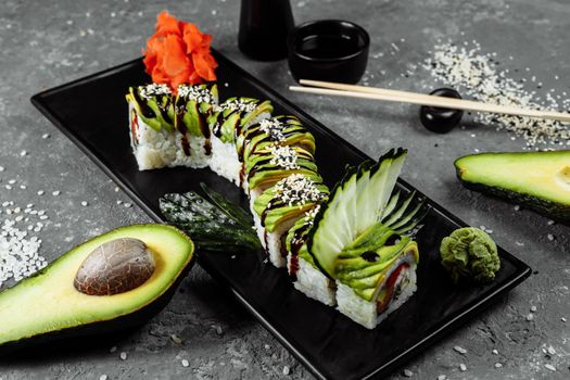 Green dragon sushi roll with eel, avocado, cucumber and ginger, accompanied with fried tempura shrimp. Traditional asian rice sushi healthy seafood.