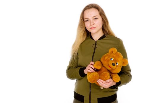 Portrait of a teenager teen girl with a teddy bear in her hands on a white background. Age of acne on face