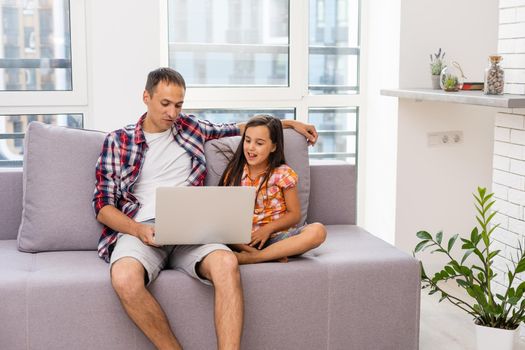 Father and daughter laughing on laptop