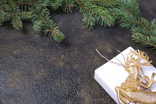 Christmas composition of fir branches, gold ribbon, gift box in craft paper on black with gold embossed background with place for text