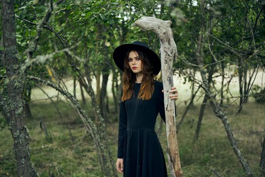 woman in witch costume in forest posing staff logic. High quality photo