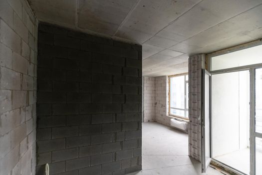 A new unfinished apartment room with the bare brick walls without decoration.