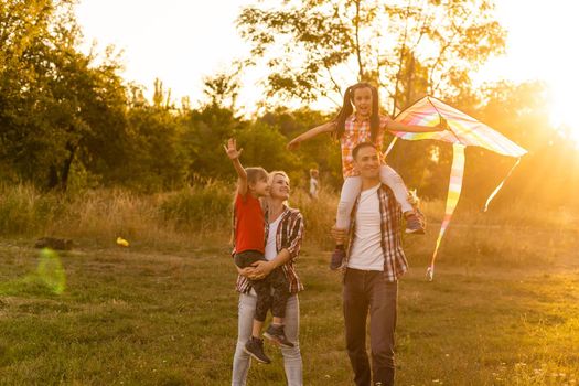 Happy family father of mother and daughters launch a kite on nature at sunset